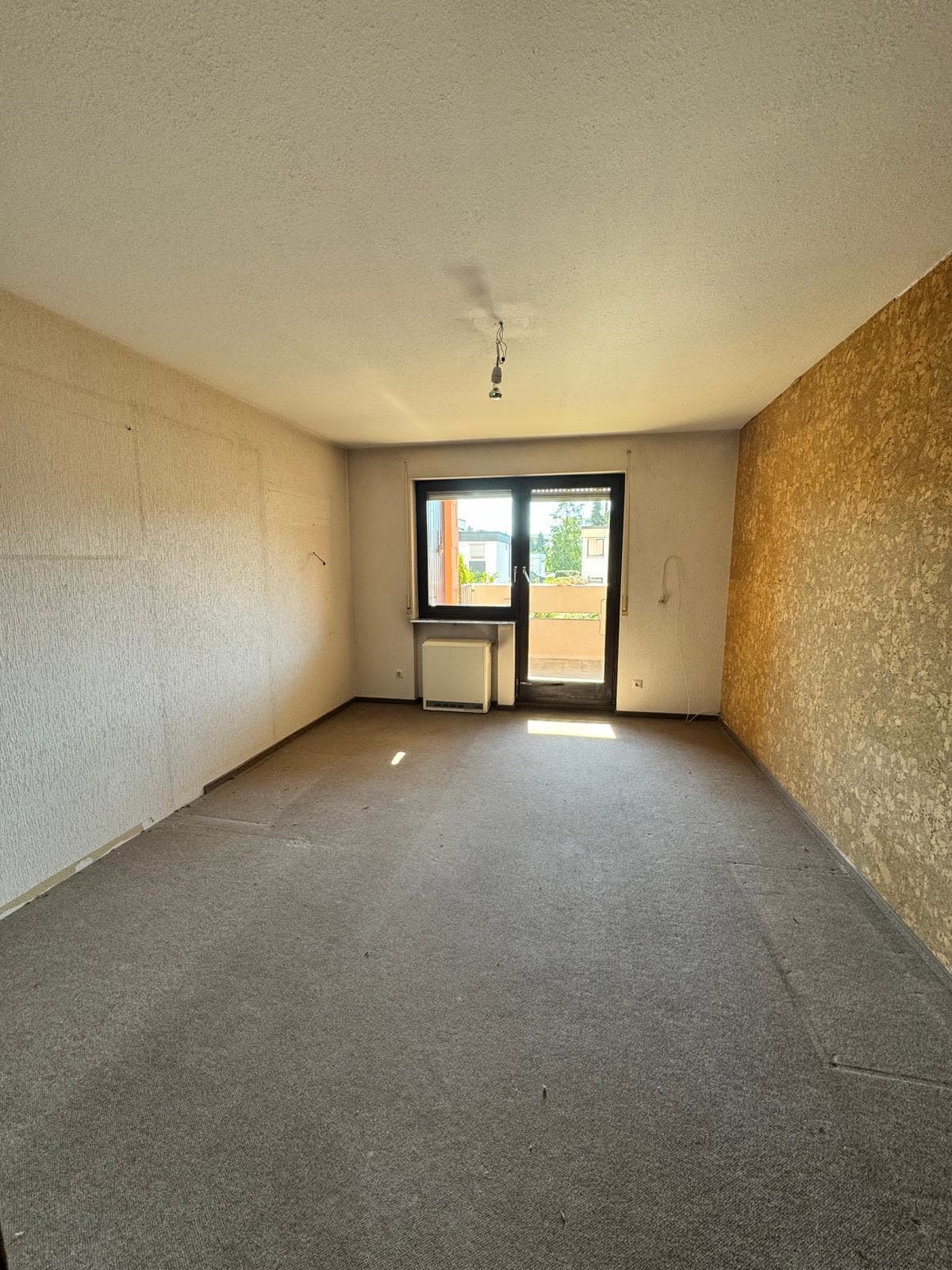 Leeres Zimmer mit Teppichboden und Balkontür nach der Räumung
