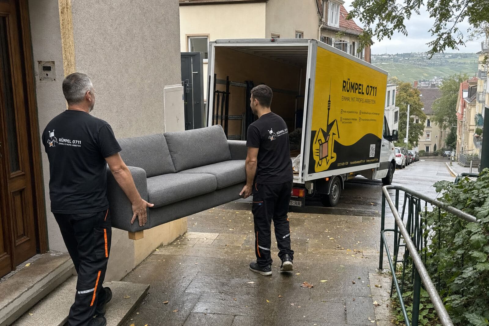 Rümpel 0711 Team trägt ein Sofa in der Stuttgarter Halbhöhenlage zum Transporter