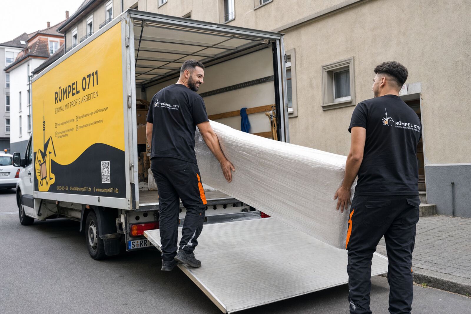 Fernumzug: zwei Mitarbeiter tragen eine Matratze über die Rampe in den Rümpel 0711 Transporter